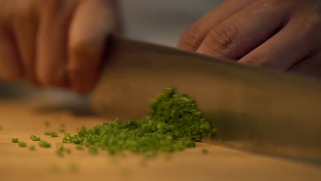 professional chef hands chopping scallion green parts to small slices using kitchen knife and wooden cutting board, chives, green or spring onions vegetable ingredient extreme close up shot 4k concept