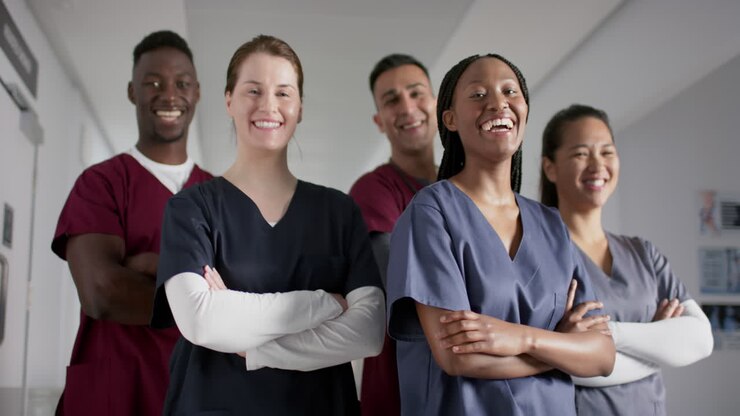 Portrait of happy diverse male and female doctors wearing scrubs in hospital, slow motion