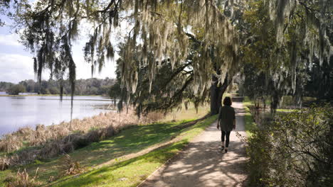 Woman-walks-under-moss-covered-trees-in-old-south-setting