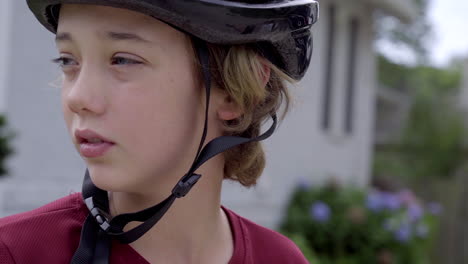 cute boy wearing a bike helmet looks to his right in slow motion, close up