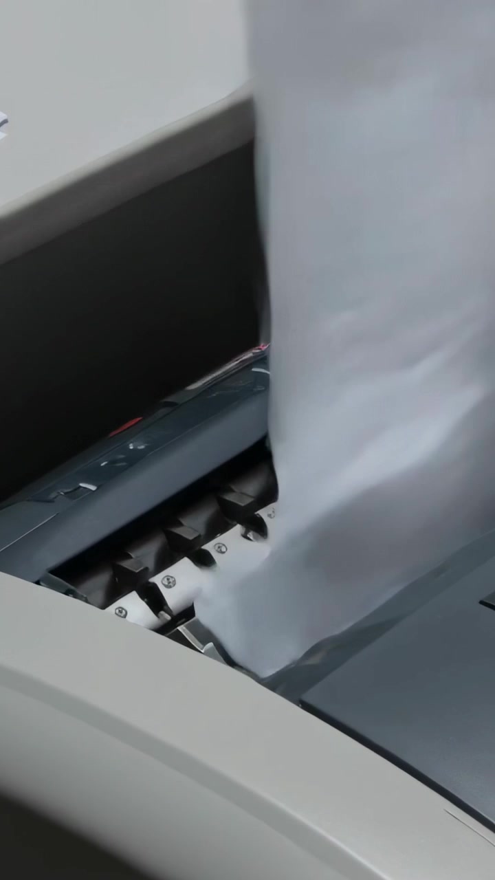 Vertical video: Lifting sheet, staff feeding into shredder with suit cuff seen at desk for disposal