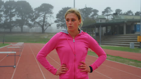 Front-view-of-Caucasian-female-athlete-walking-on-running-track-at-sports-venue-4k