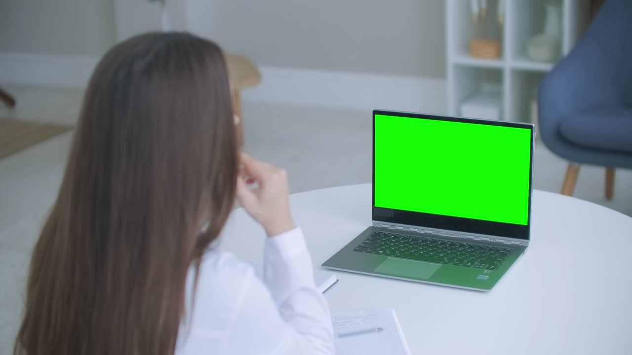 trabajador médico una mujer con una bata blanca usa una tableta en la oficina en el escritorio, chromakey en la pantalla de la tableta, una vista sobre su hombro. médico hablando con portátil con pantalla verde.