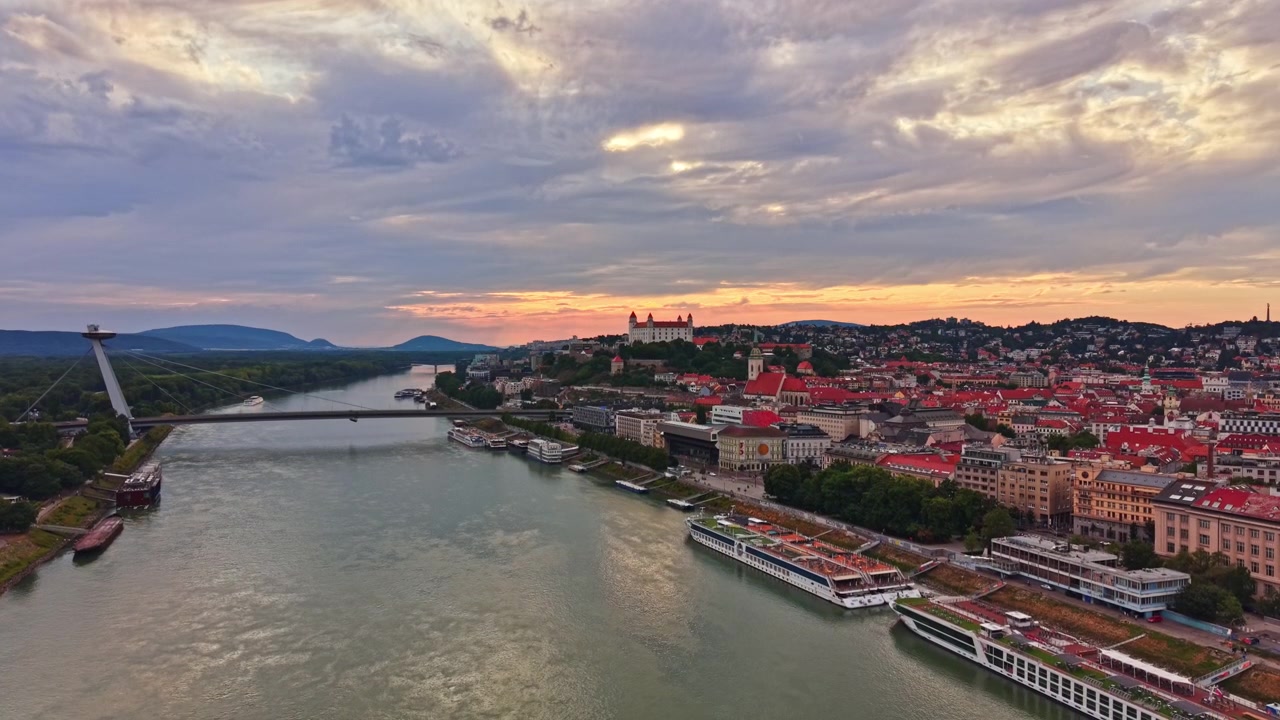 Himmel over Bratislava by under solnedgang med broer og både på floden
