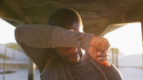 african american man wiping his forehead, taking break in exercise outdoors in the evening