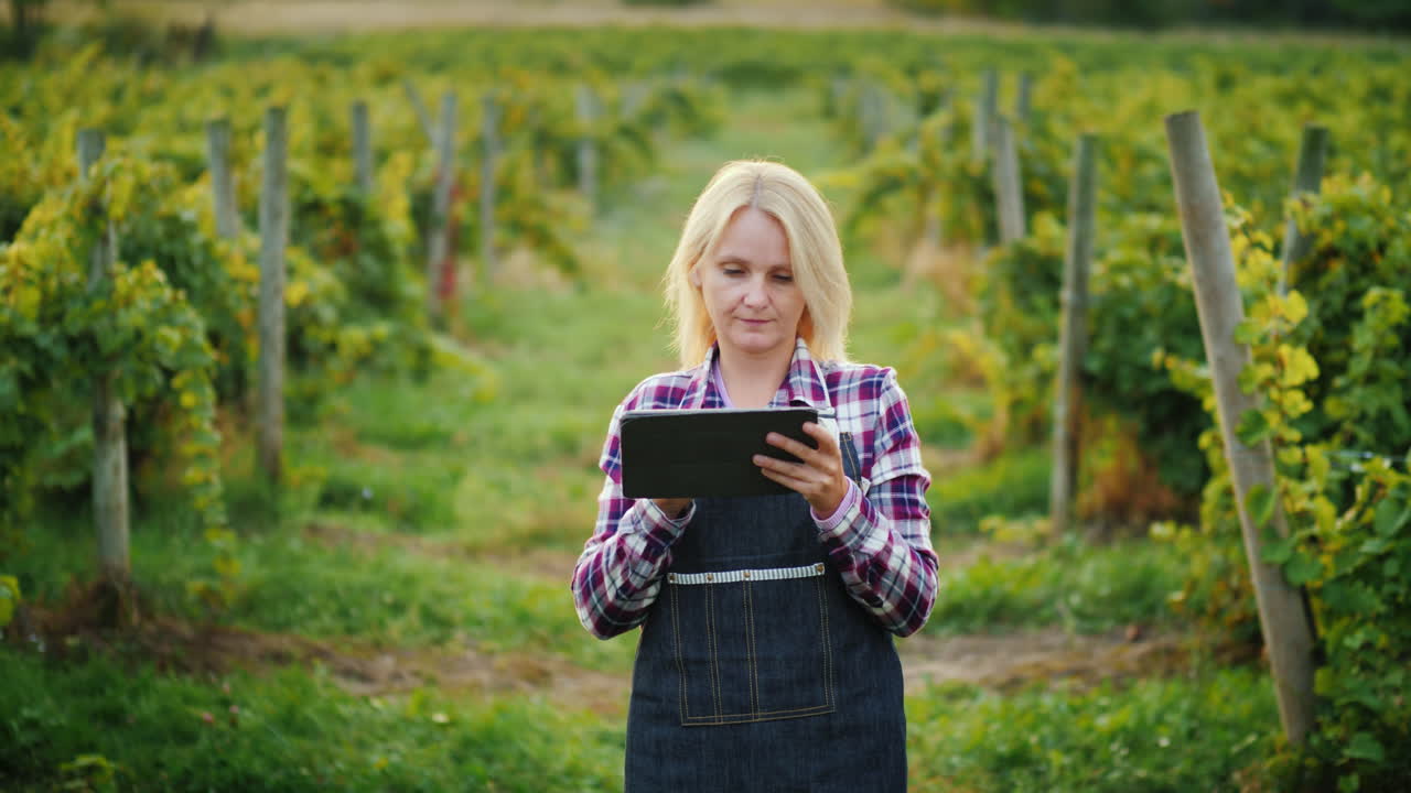 una agricultora satisfecha usa una tableta cerca de su jardín antes del atardecer