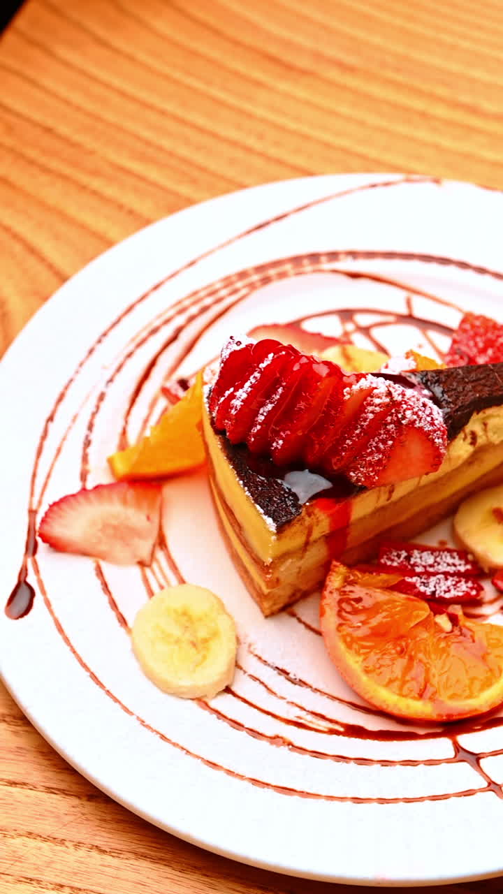 Cake slice with fruits on plate. A cake slice served with sliced bananas and strawberries on a decorated plate
