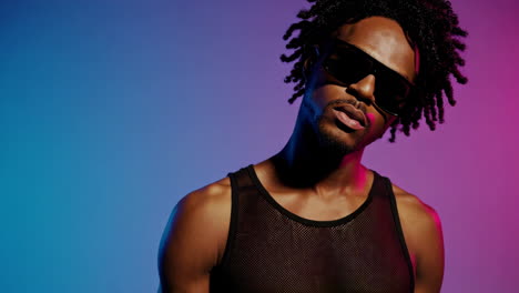stylish man with dreadlocks and sunglasses in neon lights