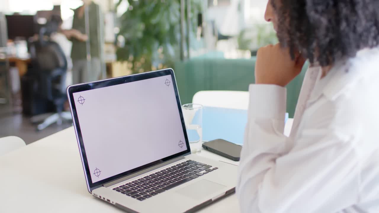 Biracial casual businesswoman in office making laptop video call, copy space on screen, slow motion