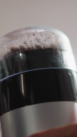 una mujer molía granos de café usando un dispositivo de primer plano. una mujer con una túnica esponjosa molina granos con un dispositivo de cocina. proceso de hacer una bebida saborosa con cafeína