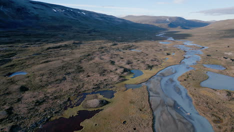 beautiful total view tracking shot of a river, that flows through a stony and barren landscape, sunny day, daylight, no people, outdoor, wilderness