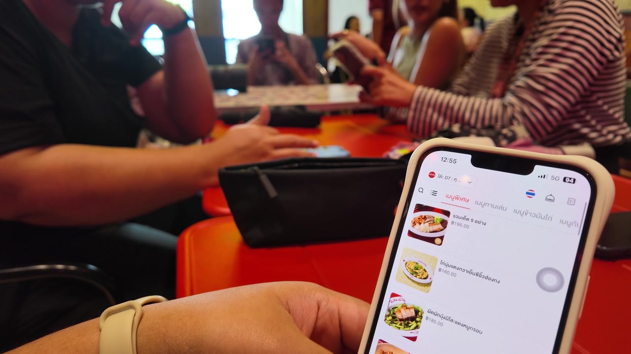 Close-up of hands scrolling through a mobile food delivery app at a restaurant table.