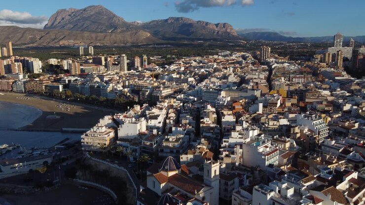 Movimento aereo all'indietro che rivela un insieme di edifici sul lungomare di Benidorm ad Alicante, Spagna.
