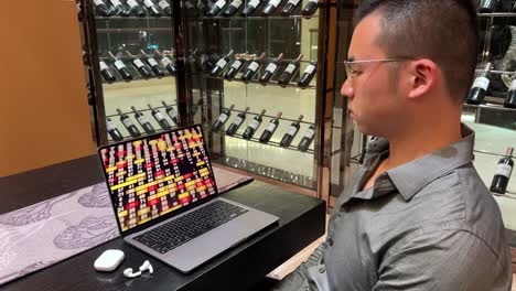 asian millennial entrepreneur man looking at numbers on laptop in luxurious home