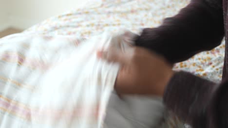 persona que hace la cama con ropa de cama floral y a rayas