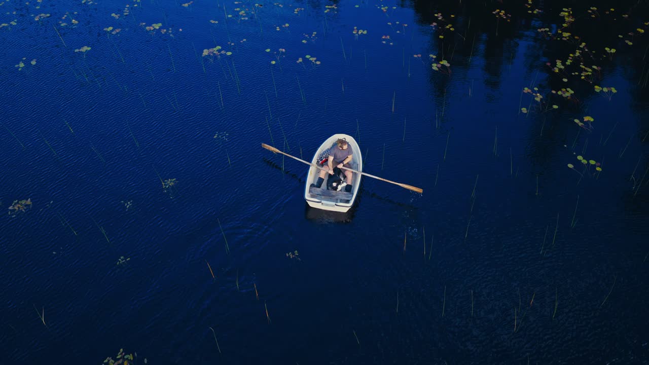 Above View Of A Person Rowing A Boat In A Tranquil Lake. Aerial Shot