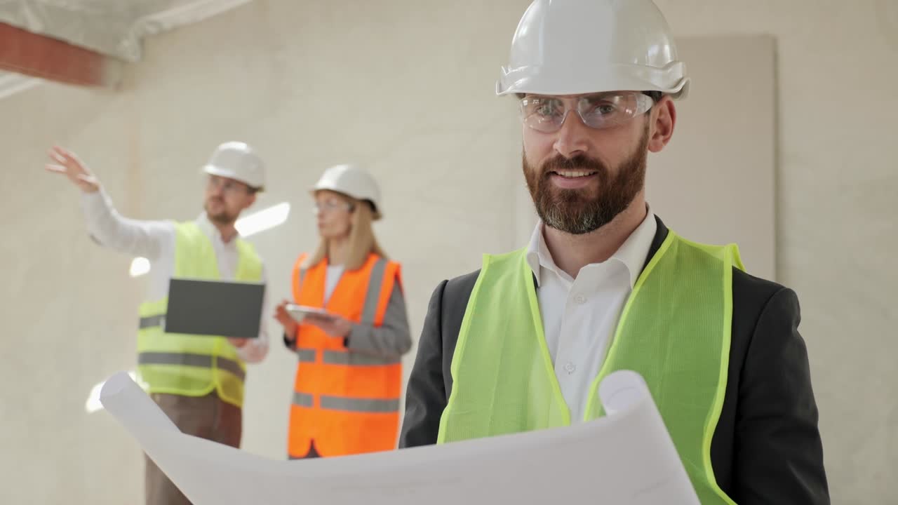 retrato de un ingeniero con casco de seguridad protector y gafas de pie en el lado de la construcción. ingenieros masculinos y femeninos sosteniendo una computadora portátil en el fondo trabajando discutiendo un nuevo proyecto inmobiliario.