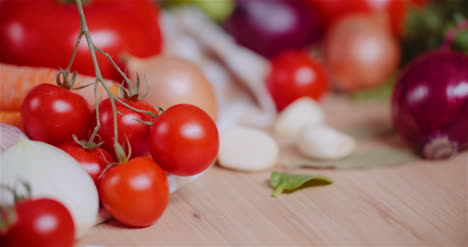 close up of various vegetables on table rotating fresh cherry tomatos carrot red onion and garlic 1