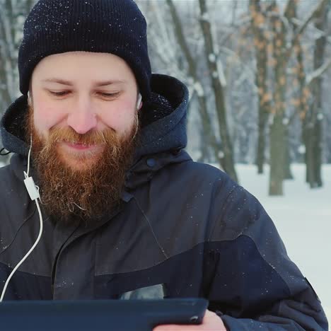 smiling man uses tablet in winter park 01