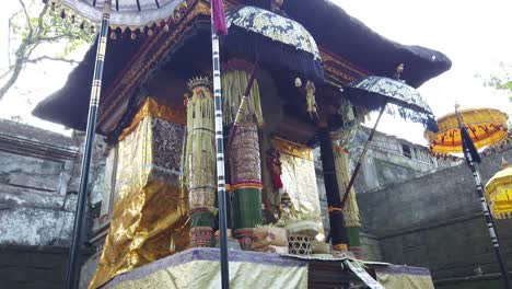balinese old temple architecture with haired black roof and colorful offerings, bali indonesia, gold ornaments and umbrellas