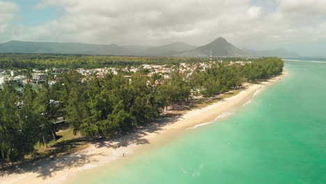 town surrounded by trees next to the beach with mountains in the background