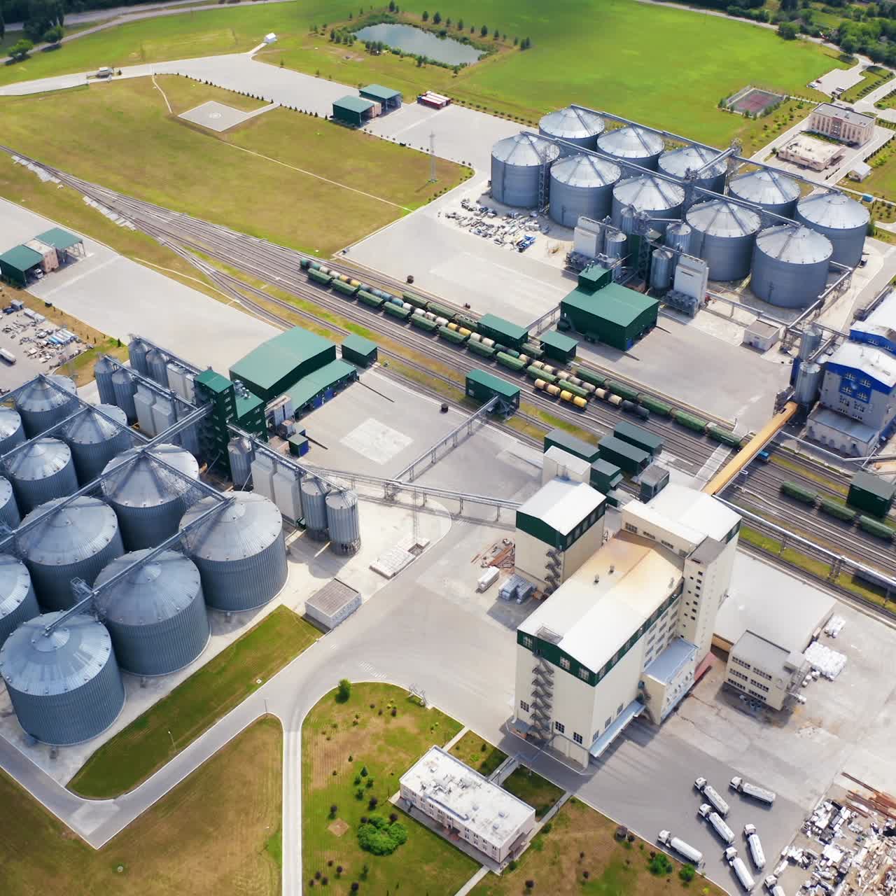 Granary for agricultural products. Flight over the aluminum containers for storing grains. Silver elevators on field. Aerial view