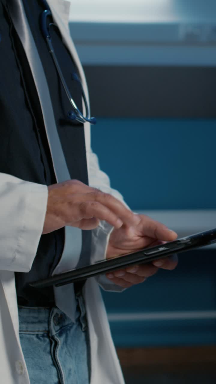 Vertical video: Close up of practitioner medic holding tablet computer searching for patient illness expertise
