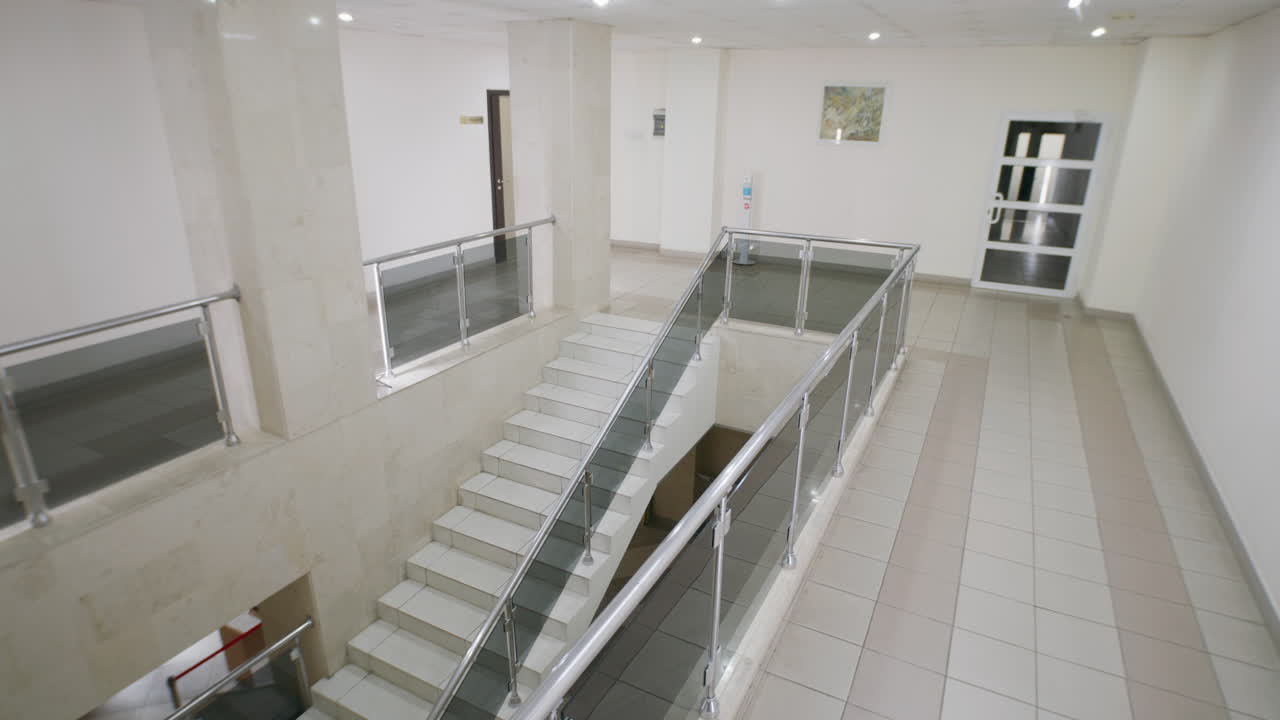People walking through a modern office building hallway with stairs