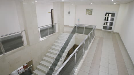 people walking through a modern office building hallway with stairs