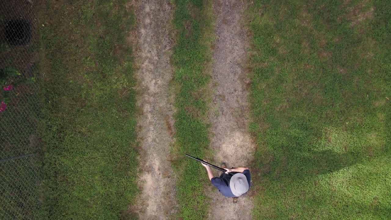 산탄총을 들고 프레임으로 걸어가는 한 남자를 똑바로 내려다보고, 중간에 멈추고 그는 펌프 액션 산탄총을 들고 장전한 다음 프레임 밖으로 걸어나갑니다.