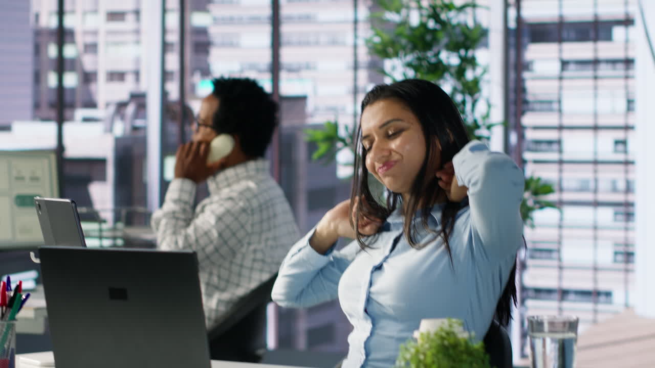 Uma mulher bocejando no escritório enquanto trabalha no laptop