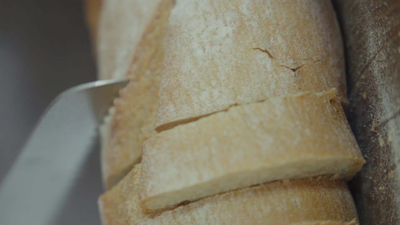 Primo piano di un coltello che affetta pane appena sfornato.