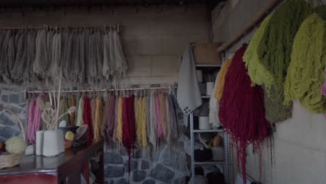 slow panning shot of lines and balls of wool and yarn hanging inside a house