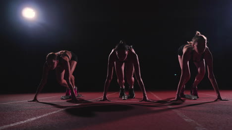 corredoras en la pista de atletismo agachadas en los bloques de salida antes de una carrera. en cámara lenta.