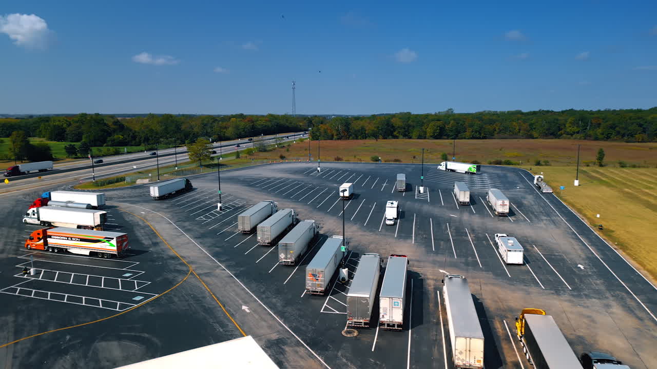 Chicago, USA, 29 June 2025: Drone aerial view of semi trucks parked at a large truck stop along the highway surrounded by green landscape