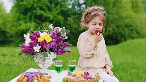 funny blonde girl sits on a table in the garden and eats her hands a delicious cake