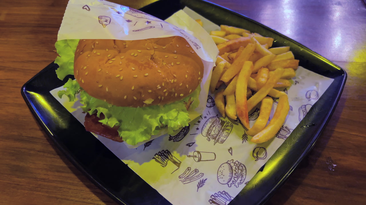 Sesame bun with lettuce served beside crispy potatoes, tabletop