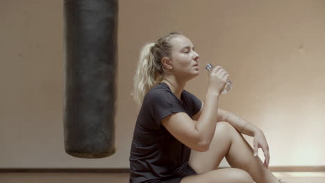 side view of cute tired sportswoman drinking water after workout