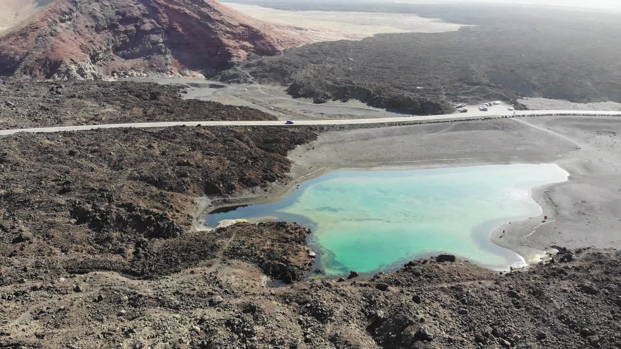 란사로테의 작은 호수 위의 회전은 뒤에 있는 화산 땅을 드러 ⁇ 니다.