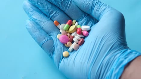 hand in blue gloves holding assorted pills