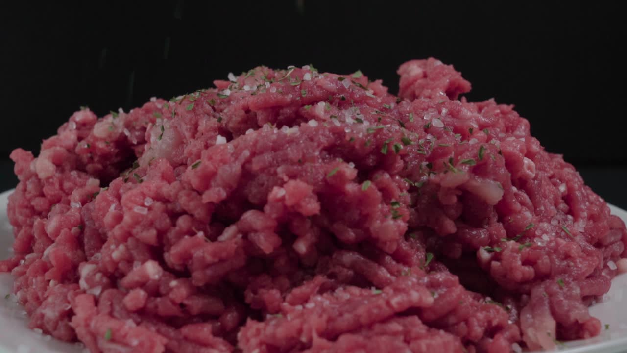 espolvorear perejil seco sobre carne molida cruda, disparo de estudio de primer plano aislado