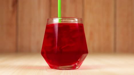 red drink poured into glass with straw