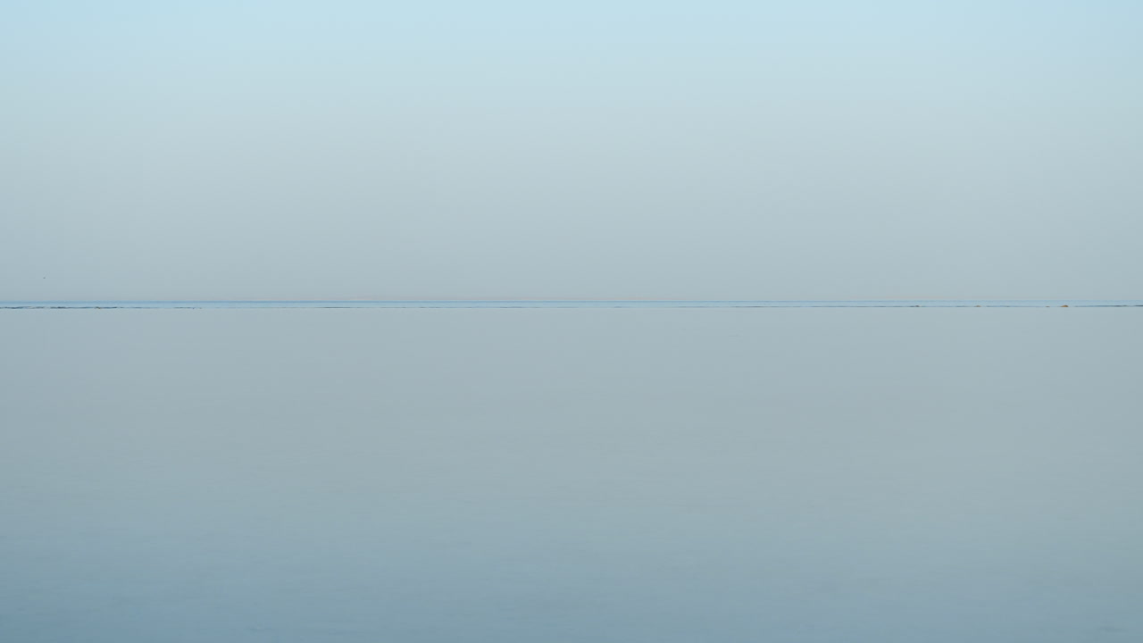 el mar en calma y el cielo se tocan en el horizonte