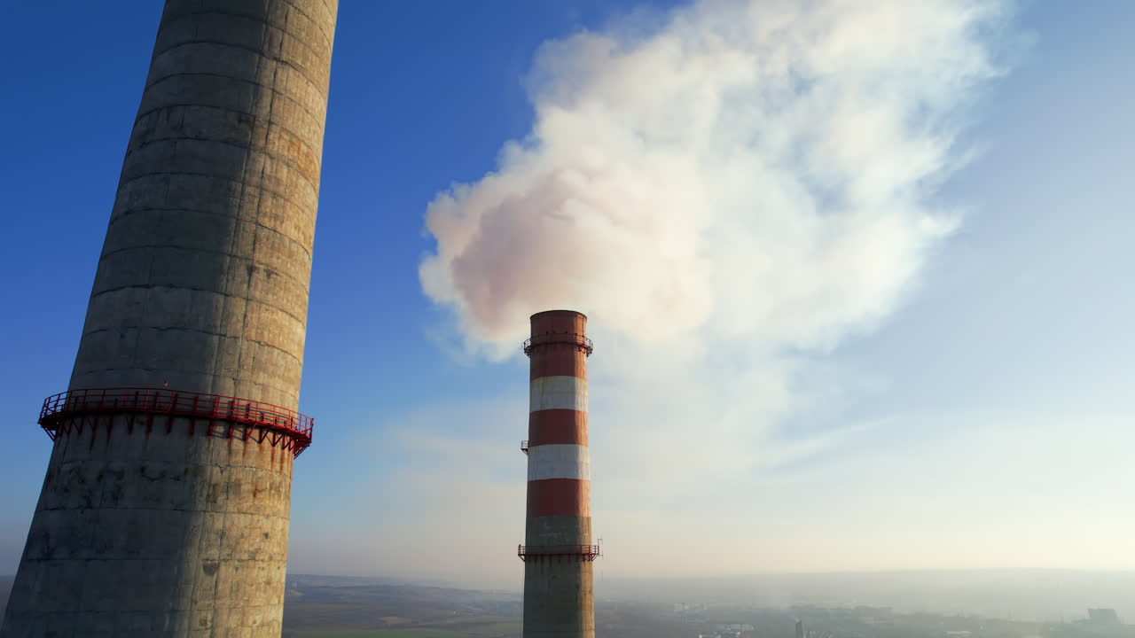 Aerial drone view of thermal power plant in Chisinau, Moldova. View of pipes with felling steam, cityscape, forest on the background