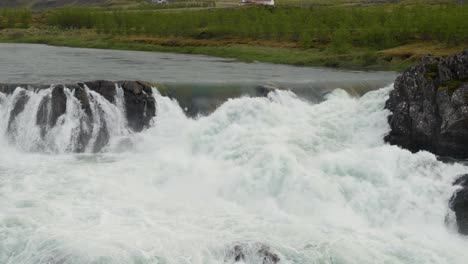 water rushing over rocks forming rapids in the icelandic countryside