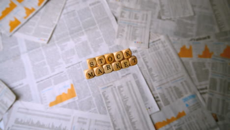 wooden dice spelling out stock market falling over sheets of paper