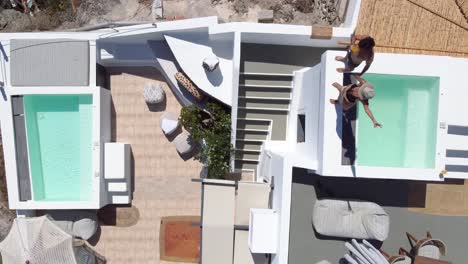 vista aérea de pájaro de una pareja disfrutando del alojamiento en la terraza del hotel, santorini, grecia
