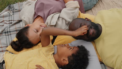 loving african american family lying on blanket outdoors