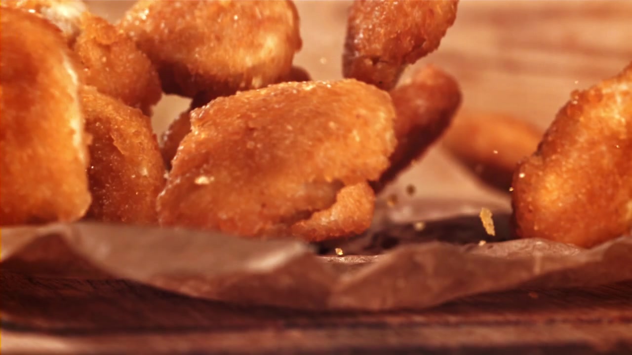 Deliziosi nugget croccanti che cadono al rallentatore su carta da forno.