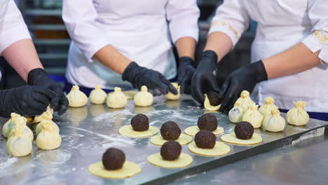 three confectioners make cookie desserts. manufacturing handmade sweets with stuffing at food factory. close up.